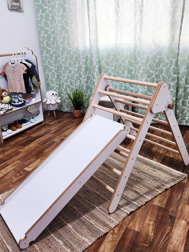The Pikler Triangle with Slide and Climbing Ramp is an expanded version of the well-known Pickler Triangle toy, which includes a slide and climbing ramp. This toy is designed to help children develop their motor skills, balance, and self-confidence through exploration and active play.